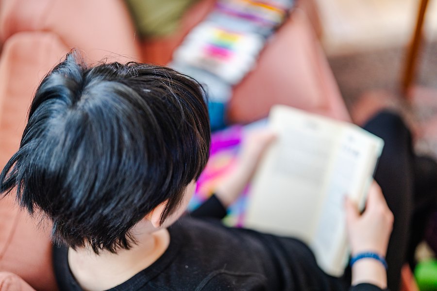 Ett barn sitter i en soffa och läser en bok